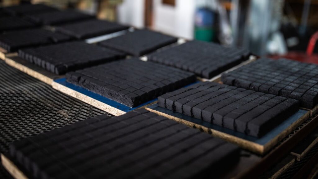 A neat stack of premium low ash coconut charcoal briquettes from Tatum Nusantara, showing their perfect cube shape and clean texture.