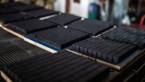 A neat stack of premium low ash coconut charcoal briquettes from Tatum Nusantara, showing their perfect cube shape and clean texture.